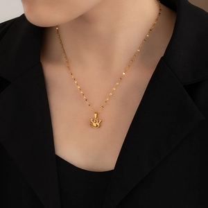 Detailed view of a gold crab pendant necklace on a model wearing a black blazer