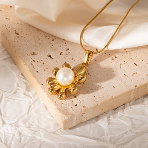 Detailed macro shot of a 18K gold-plated flower pendant with a white round pearl center