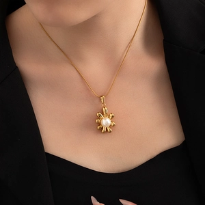 Detail of 18K gold plated flower pendant with a white pearl on a sleek snake chain