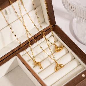 Detail of golden stainless steel necklace set with ocean dolphin and whale charms