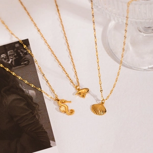 Detailed close-up of golden crab, seahorse, and shell pendants on fine link chains