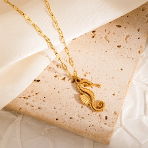 Detailed close-up of golden seahorse pendant with wave texture on stone display