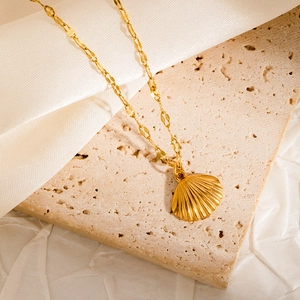 Detailed close-up of a golden scallop shell pendant on a fine necklace chain