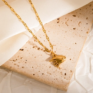 Close-up of golden crab pendant necklace with textured wave chain on silk fabric