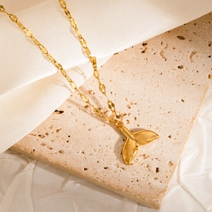 Detailed view of a golden crab pendant necklace on a stone surface with silk fabric