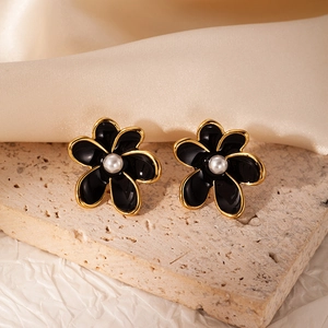 Close-up of vintage flower stud earrings with black enamel petals and white pearl centers
