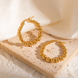 Detail of beaded 18k gold plated hoop earrings featuring a polished lever back closure