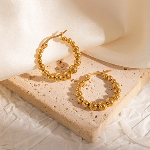 Detailed view of 18k gold plated hoop earrings with gradient beads on beige marble