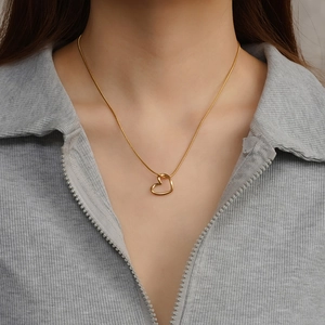Eleganter goldener Herzanhänger an einer Schlangenkette, von einem Model getragen