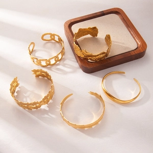 Macro view of five unique gold plated stainless steel open bangles with textured patterns