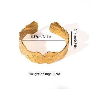 Detailed close-up of gold leaf-shaped open cuff with hammered metal texture and measurements