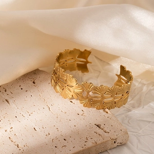 Detailed view of gold-plated open bangle featuring intricate hollow ginkgo leaf patterns