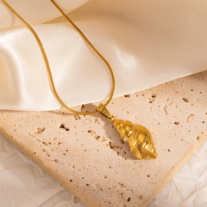 Golden 304 stainless steel conch pendant necklace on an elegant travertine display