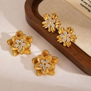 Boucles d'oreilles fleurs vintage dorées avec cristaux sur fond de lin rustique