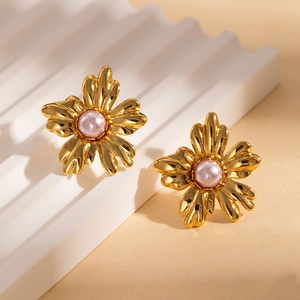 Détail macro de boucles d'oreilles fleurs dorées vintage avec perles rose clair