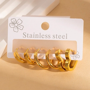 Three-piece gold stainless steel hoop earring set with heart-shaped studs on white card