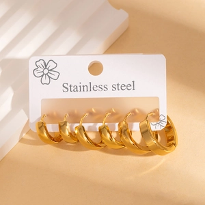 Three pairs of thick gold stainless steel hoop earrings on a floral display card