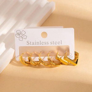 Close-up of golden stainless steel hoop earrings and geometric studs on a display stand