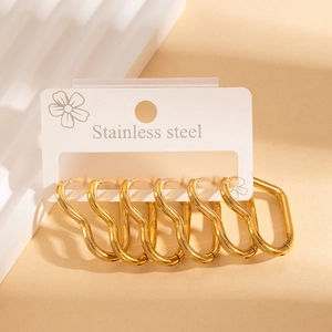 Detail of three pairs of wavy golden stainless steel hoop earrings on display card