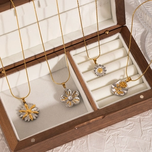Minimalist stainless steel flower necklace set with daisy and rose pendants on wood