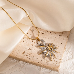 Macro shot of a spiral shell sun pendant in silver and gold on a beige stone