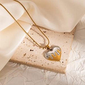 Macro detail of bicolour lava heart pendant on a gold snake chain over stone texture