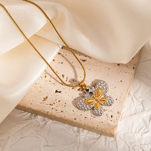 Detail of two-tone gold and silver butterfly pendant on a gold snake chain necklace