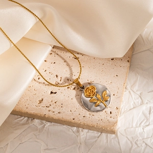 Detail of vintage embossed rose pendant on gold twist chain over stone background