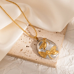 Detailed view of dual-tone oval locket with gold dragonfly relief on silver base