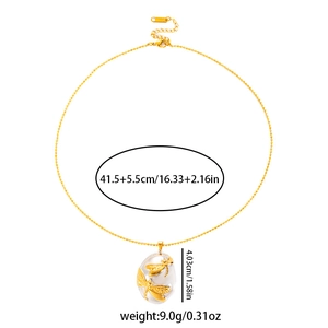 Detailed view of gold dragonfly pendant with cream inlay and dimension measurements