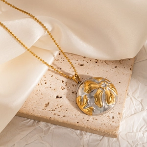 Detailed shot of bicolor floral relief pendant with zircon on a gold bead chain