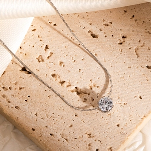 Detailed macro view of a silver necklace featuring a sparkling round claw-set diamond charm
