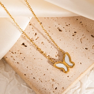 Close-up of gold butterfly pendant necklace with white inlay on elegant silk and stone