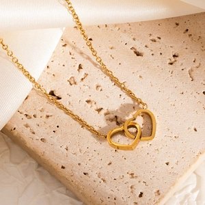 Detail view of interlocking double heart gold necklace on a stone display pedestal