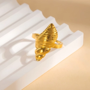Dettaglio dell'anello a conchiglia dorato con texture a spirale su supporto bianco a onde