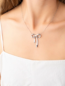 Detailansicht einer silbernen Schleifenkette mit Perle am Hals eines Models