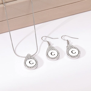 Waterdrop shaped silver necklace and earrings set featuring letter C and crystal border