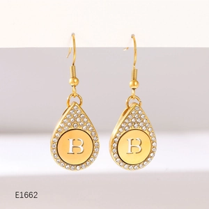 Detail of gold teardrop earrings with pavé crystals and letter B engraving