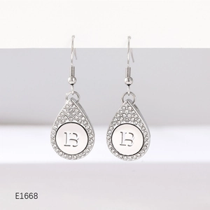 Detail of silver drop earrings with pavé stones and engraved letter B pendant