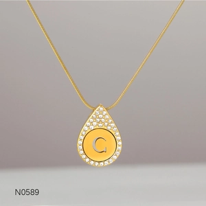 Close-up of gold water-drop necklace with Zircon inlay and letter C engraving
