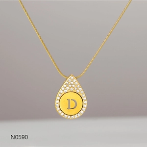 Macro view of gold letter D pendant with sparkling rhinestones on snake chain