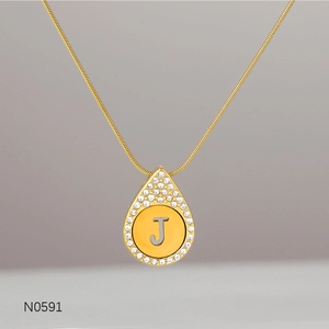 Close-up of gold water wave chain with a teardrop pendant featuring the letter J