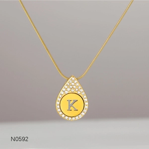 Detail of gold snake chain necklace with a rhinestone letter K teardrop pendant