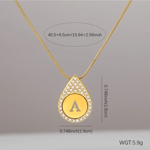 Close-up of golden teardrop pendant with letter A engraving and zircon frame