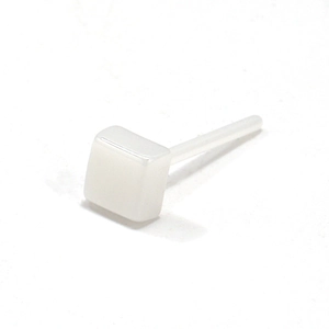Detalle macro de pendientes minimalistas cuadrados de cerámica blanca con bordes redondeados