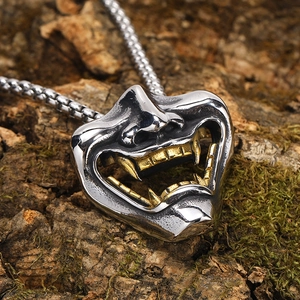 Dettaglio macro del ciondolo maschera Hannya argento e oro su catena su corteccia