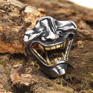 Dettaglio macro dell'anello maschera Hannya argento e oro su legno naturale e muschio