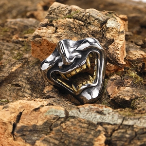 Macro del ciondolo maschera Hannya in argento con denti dorati su sfondo di legno vero