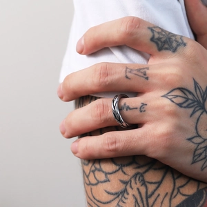 Detailed macro shot of a silver braided stainless steel ring on a tattooed hand