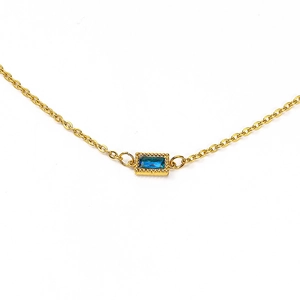 Detail of a minimalist gold O-chain necklace featuring a rectangular blue zircon pendant